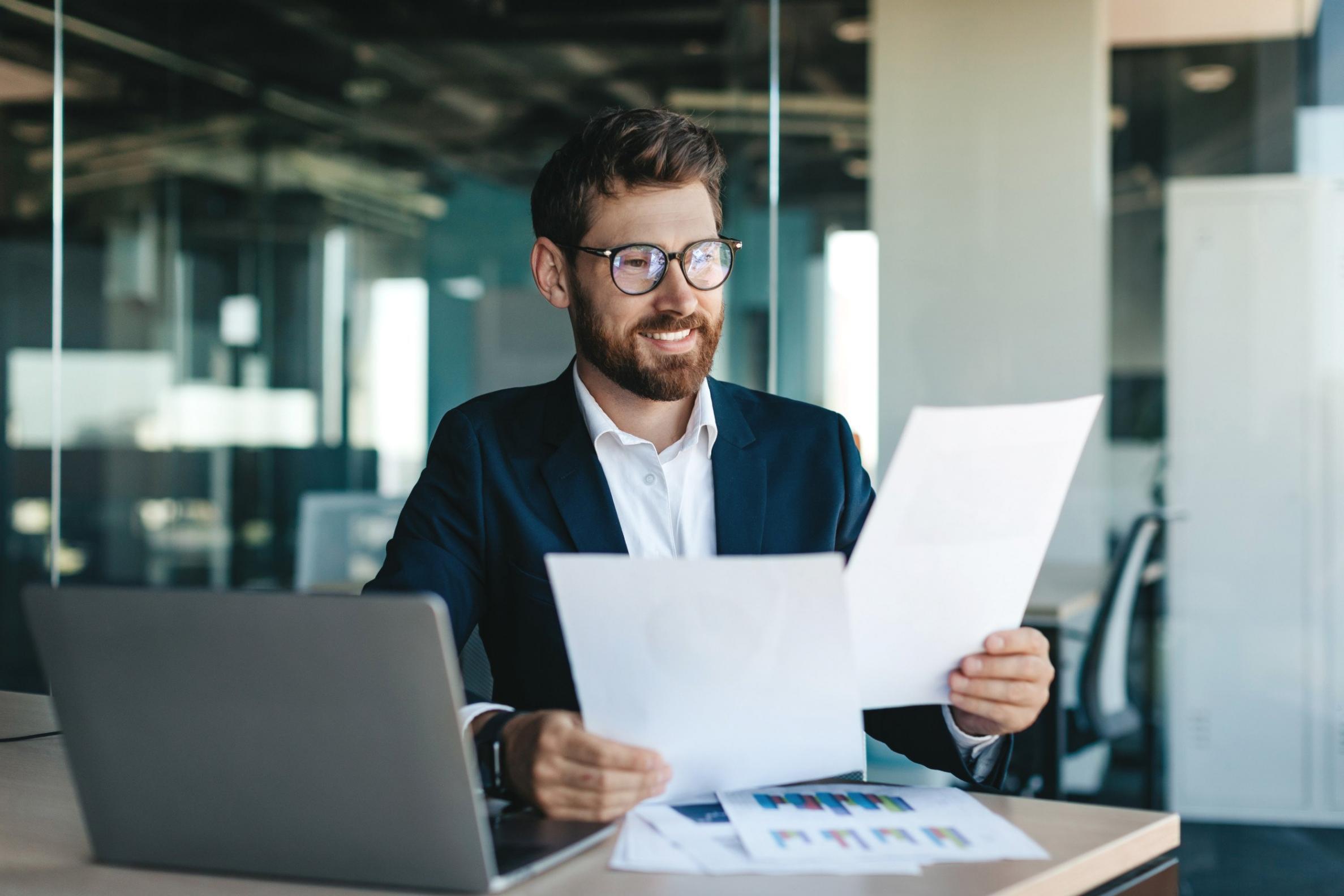 Young professional reviewing financial documents at home desk